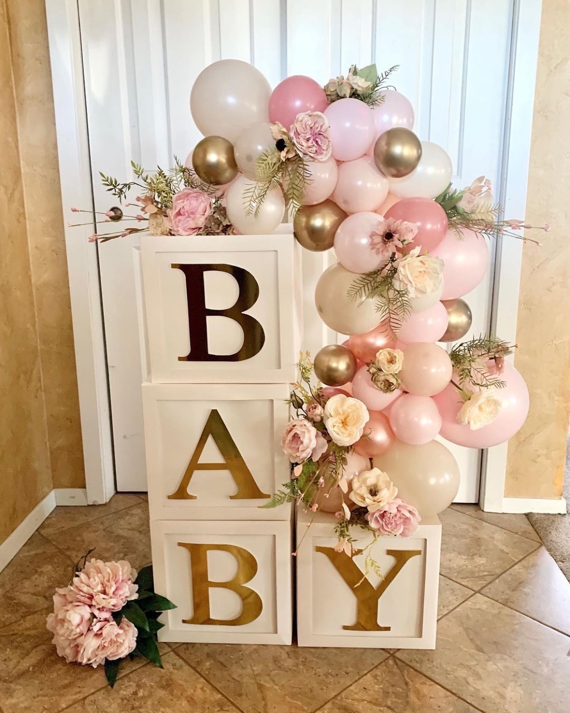 Pink cream and gold balloon décor with flowers and baby letter blocks