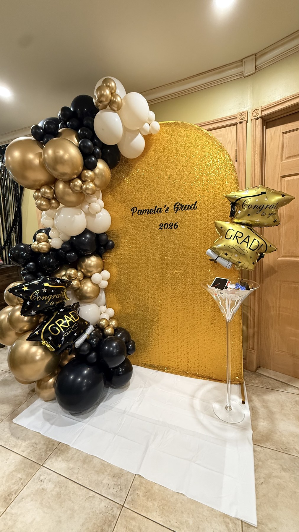 Gold black and white graduation balloon arch with shimmering gold backdrop