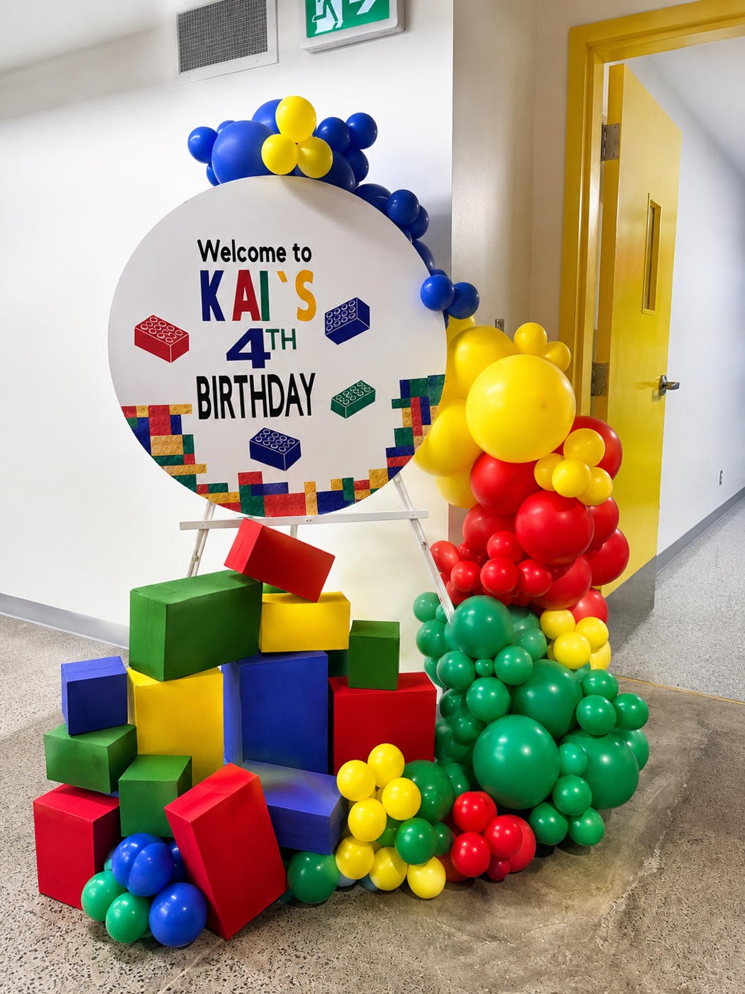 Colourful LEGO fourth birthday balloon décor with custom welcome sign and block props