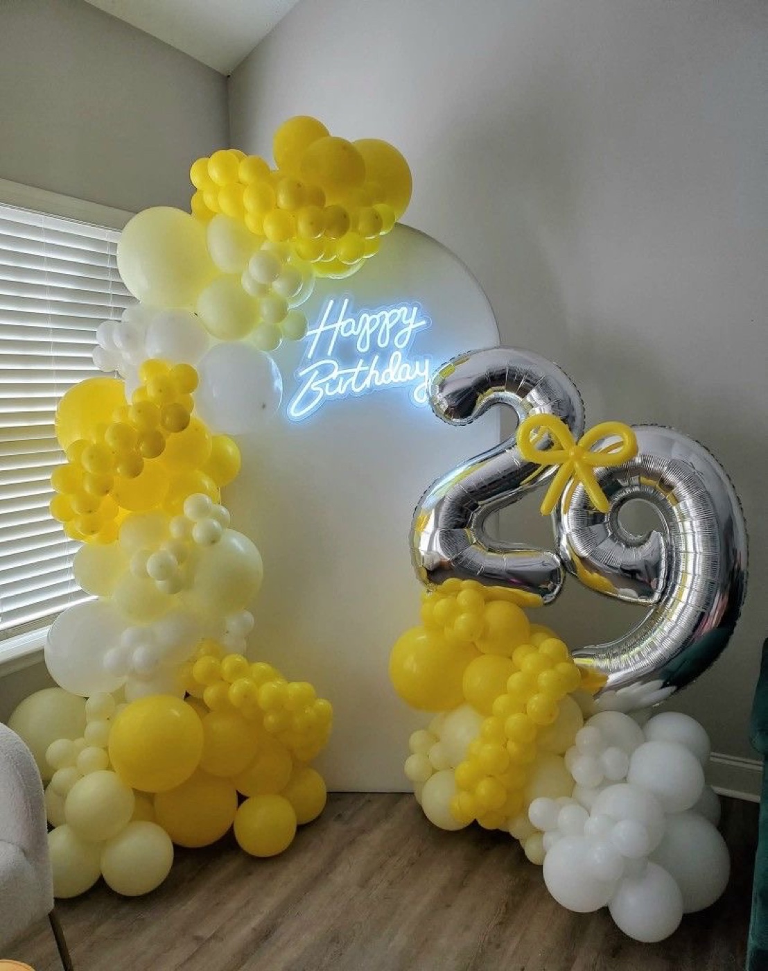 Yellow and white 29th birthday balloon setup with illuminated sign